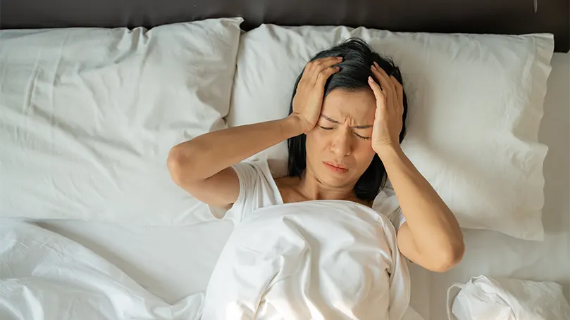 Una mujer en la cama que sufre vértigo mientras duerme.