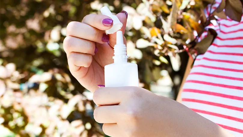 Una mujer con un spray nasal en la mano.