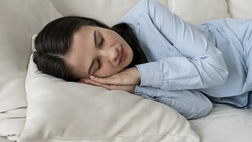 Imagen de una mujer durmiendo en un sofá con espacio limitado.